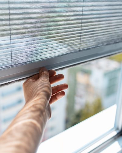 Close-up of male hand trying to open the modern mosquito net on plastic window.